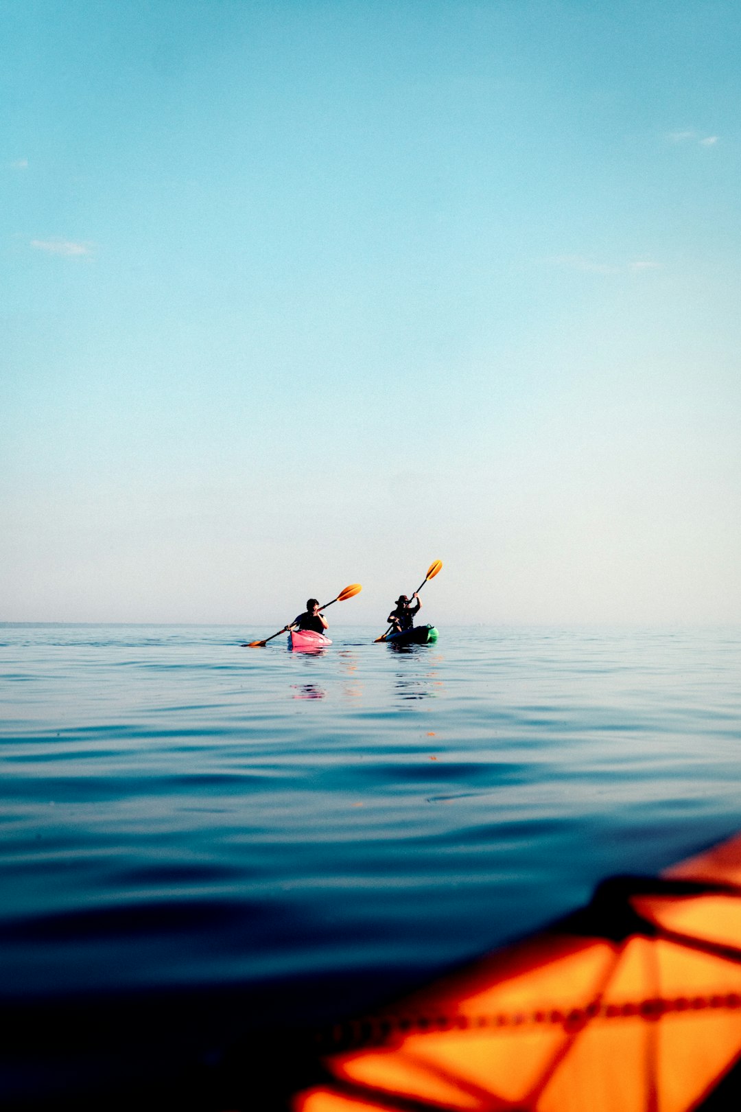 Two kayakers paddling calm turquoise water in Casco Bay