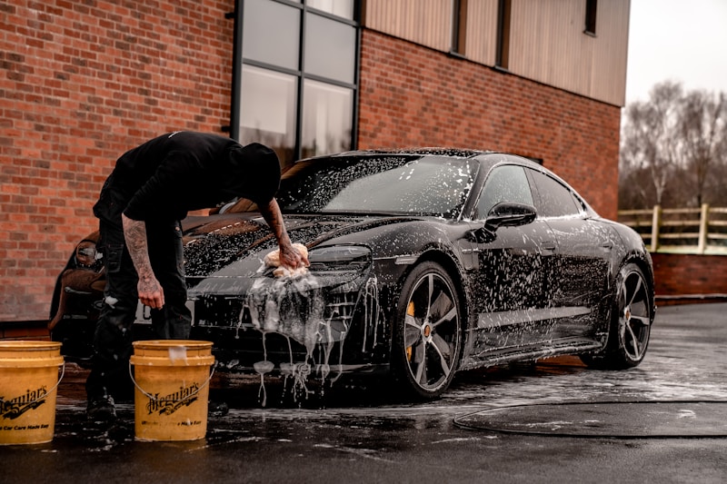 Professional washing a black sports car with foam
