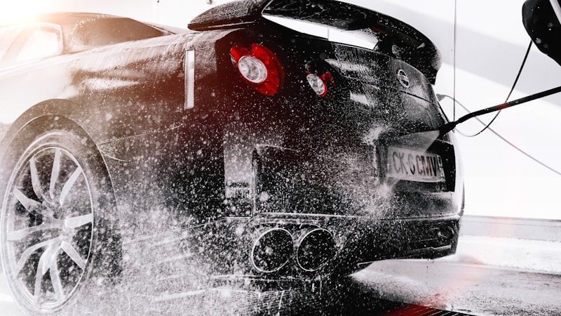 High-pressure water spray cleaning a black sports car